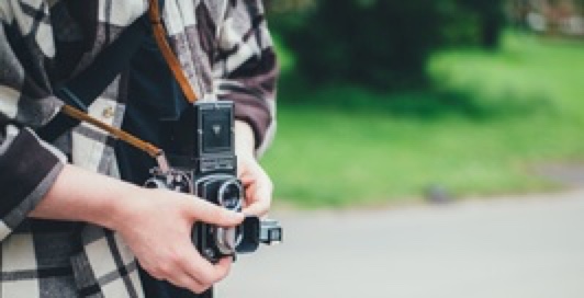 Closeup of a professional camera strapped around a person